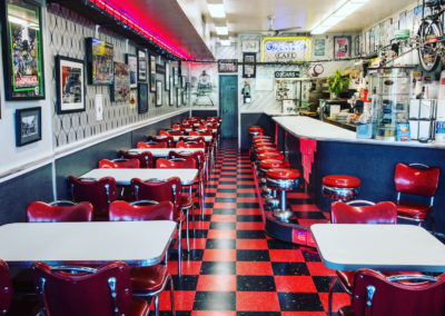 a restaurant dining room with tables, a counter, a bright red and black checkerboard floor and wall decorations