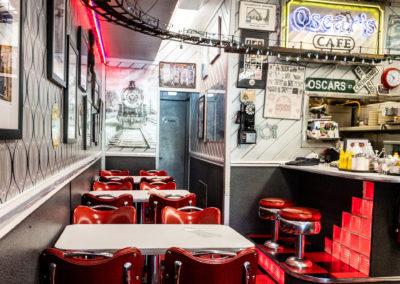 A 50's-style diner interior with tables, chairs and a service counter