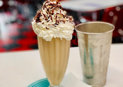 A chocolate milkshake topped with whipped cream and chocolate sauce